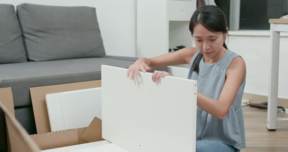 Woman assembling furniture at home