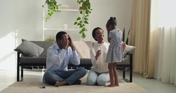 Family Playing Hide and Seek Sitting on Floor in Cozy Living Room Afro American Parents Spend Time