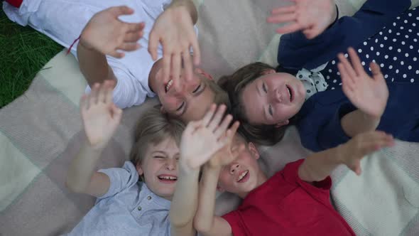 Top View Charming Kids Waving Laughing in Slow Motion Lying on Blanket Outdoors