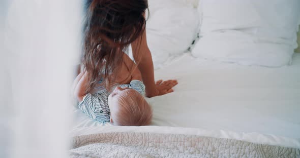 Happy Mother Playing Together with Little Cute Kid in Bedroom