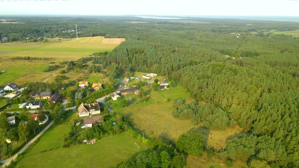 Aerial - flying over private houses surrounded with green leafy forest in Sasino village, Poland on