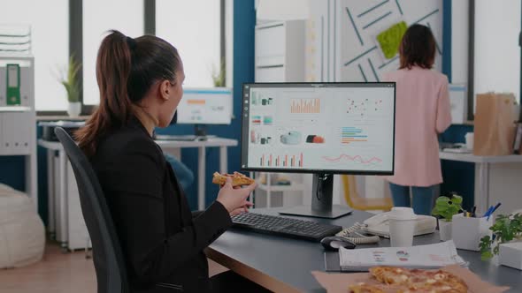 Closeup of Businesswoman Eating Tasty Pizza While Analyzing Financial Statistics at Desk in