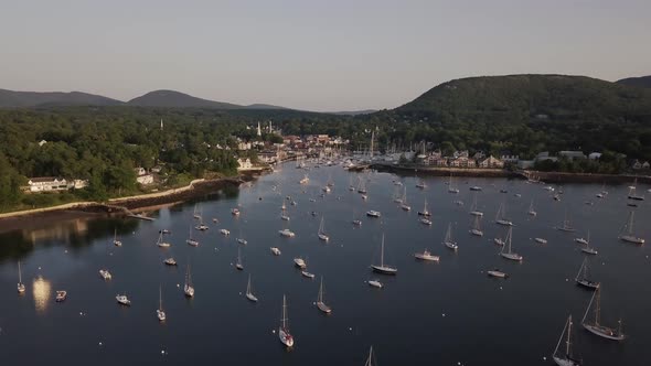 Aerial footage of an early morning flight over Camden harbor featuring many tall masted yachts and t