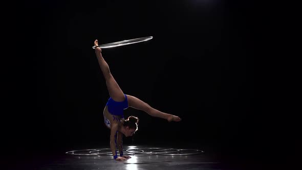 Gymnast in a Bright Outfit Twists a Hoop on Her Arm and Then on Her Leg