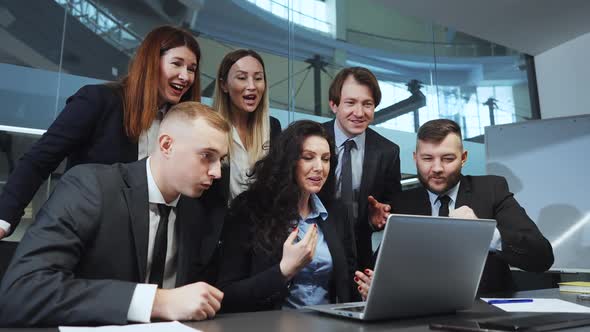 Business Team Following News on Laptop and Gaining Success