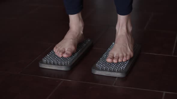 Female bare feet stand on wooden sadhu board with sharp nails. Yoga practice. Auserity. Close up 4K