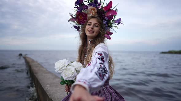 Smiling Beautiful Ukrainian Young Woman with Bouquet of Flowers Stretching Hand Looking at Camera