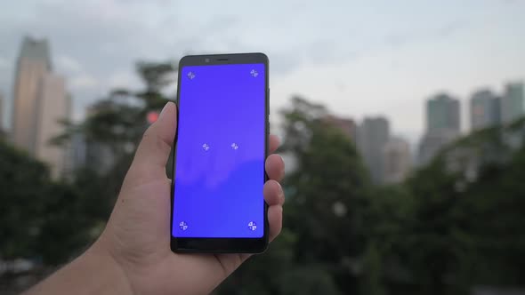 A young tourist businessman uses a mobile phone in futuristic city background.