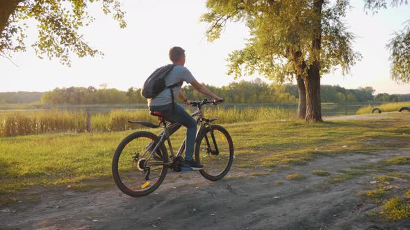 Teenage Boy Rides Bike in City Park at Sunny Day. Healthy Lifestyle Concept