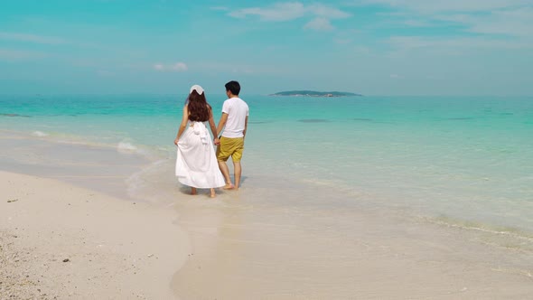 happy young couple walking on the sea beach at Koh MunNork Island, Rayong, Thailand