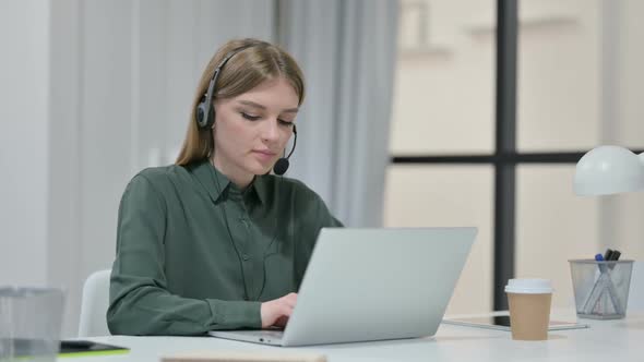 Woman Talking on Headset While Working on Laptop