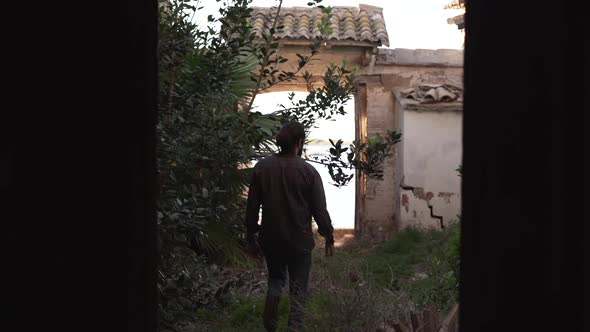 Male silhouette facing plants and arc and standing in front of camera