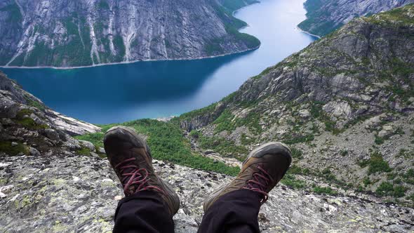 View at the abyss with hiking shoes and legs in foreground.