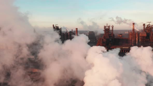 Drone Around Toxic Enterprise Chimneys Tubing Against the Sky Background Release Black Smoke