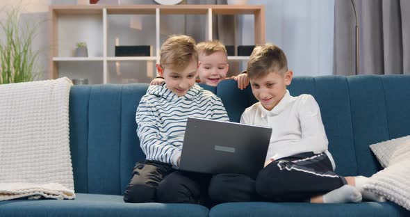 Boy Couch on which Sitting His Eldest Brothers and Watching on Computer