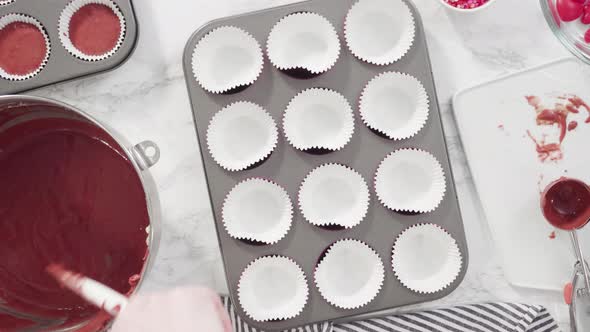 Flat lay. Step by step. Scooping cupcake batter into foil cupcake cups to bake red velvet cupcakes.