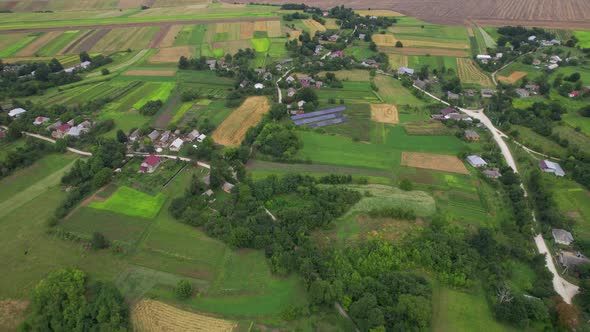 Aerial View From the Flight Over a Typical Old Village with Fields Solar Station and Road in Summer