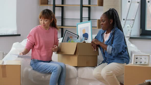 Women Moving to New Home and Unpacking Boxes