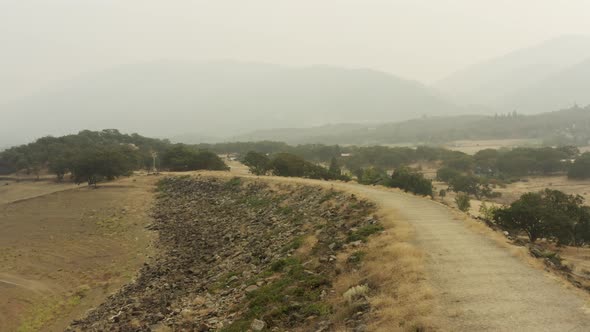 Slowly rising drone aerial showing drought and smokey conditions in summer, smoke hangs in the air c