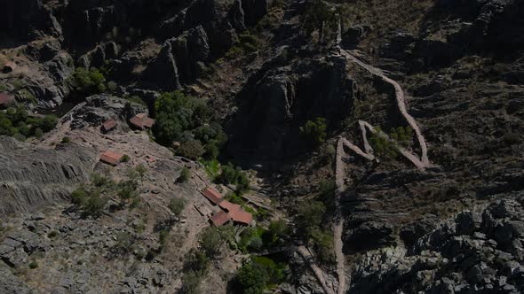 Old rural village and castle on rock spur, Penha Garcia in Portugal. Aerial forward tilt up reveal