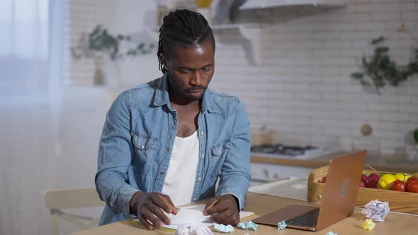 Middle Shot of Angry Stressed African American Man Tearing and Crumpling Paper Working Online at