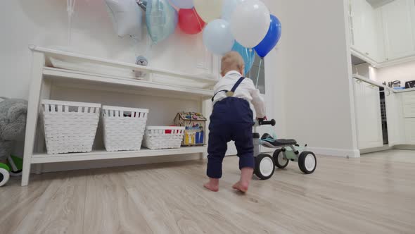 Kid on Baby Bicycle Balance Bike for Toddlers with Colorful Balloons 1 Year Old Baby Boy Celebrating