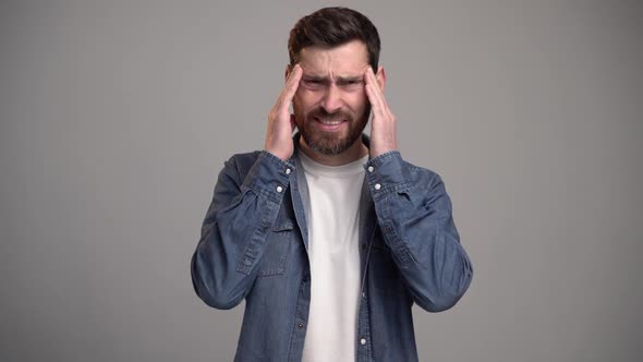 Unhappy frustrated bearded man massaging temples feeling headache, suffering migraine