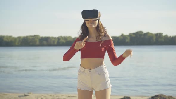 Middle Shot of Positive Young Woman in VR-googles Moving Hands and Smiling. Beautiful Brunette