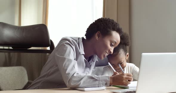 Cute Small 6-7 Years African Kid Daughter Learning Writing with Young Mixed Race Mom Tutor. Adult