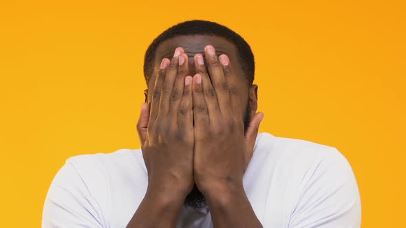 Shocked Afro-American Man Peeping Through Fingers Against Yellow Background