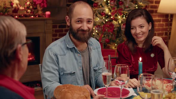 Happy Man Sitting at Christmas Dinner Table with Close Relatives