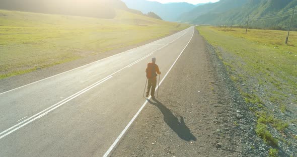 Flight Over Hitchhiker Tourist Walking on Asphalt Road. Huge Rural Valley at Summer Day. Backpack