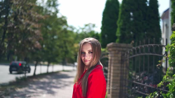 Woman walks down the street. Young smiling woman look at camera, walking in the city streets