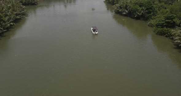 Aerial Camera Follows Small White Boat Sailing Very Slow Along Beautiful Calm River