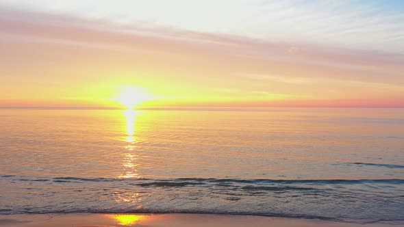 Aerial View Above The Waves Hit The Shore At Yellow Sunset.