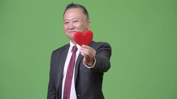 Mature Japanese Businessman Holding Red Heart Ready for Valentine's Day
