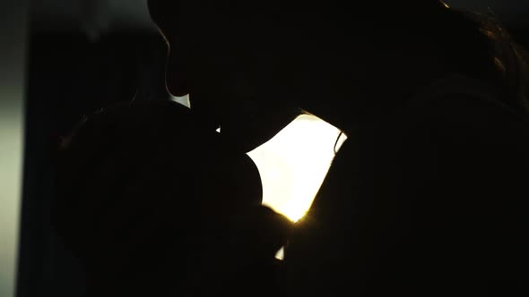 The Dark Silhouette of Mother Amusing Her Newborn Baby on Light Window's