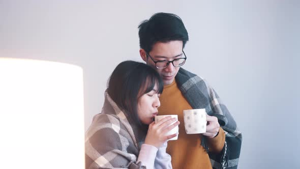 Young Asian Couple Drinking Hot Tea and Watching a Movie