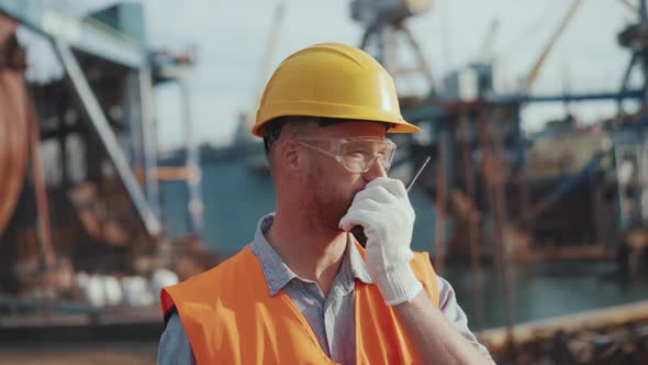 Serious man engineer in uniform talking into walkie-talkie