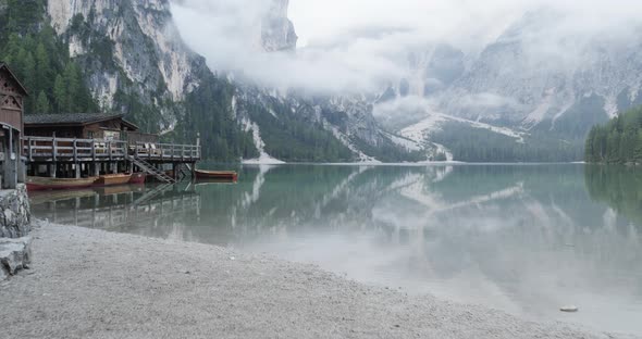 POV Walking to Boathouse with Wood Pier and Boats on Braies Lake in Cloudy Day