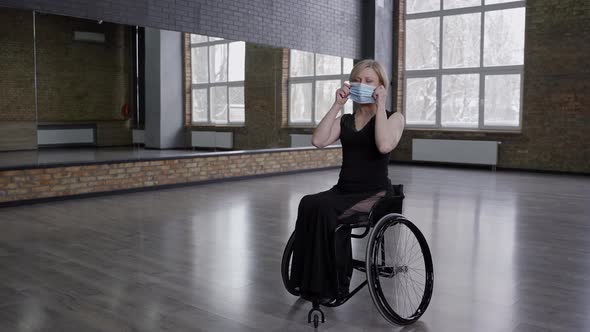 Woman Dancer on Wheelchair Putting on Mask Indoors