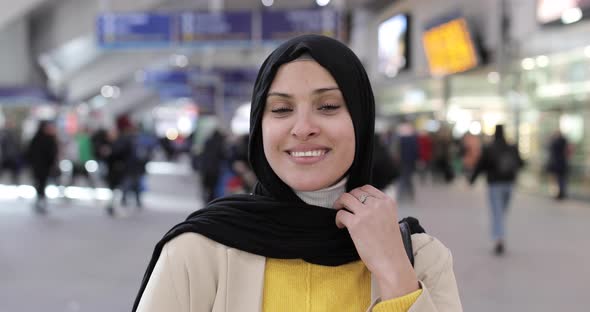 Smiling woman wearing hijab looking at camera at station