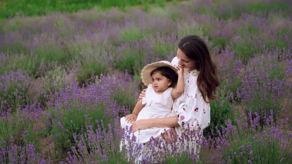 Woman Hugging and Kissing Baby Daughter in Lavender Field