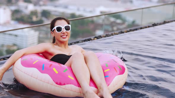 Asian young woman relaxing in swimming pool at luxury hotel