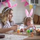 charming woman and her two-year-old son in bunny ears paint Easter eggs with paints - VideoHive Item for Sale