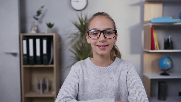 Smiling 15-Aged Girl in Glasses Posing on Camera on the Background of Her Room