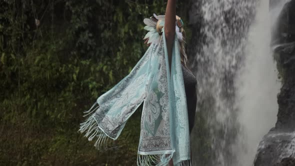 Young Girl Perfoming Meditative Dance on a Rock Close to Stream of Falling Water