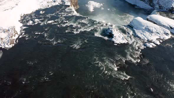 Aerial View of Godafoss Waterfall with Snowy Shore and Ice. Iceland. Winter 2019