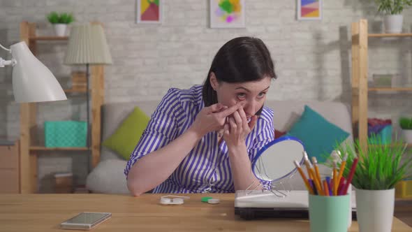 Young Woman Puts on Contact Lenses Sitting at a Table