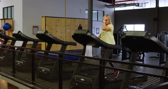 Woman doing exercise on treadmill in fitness studio